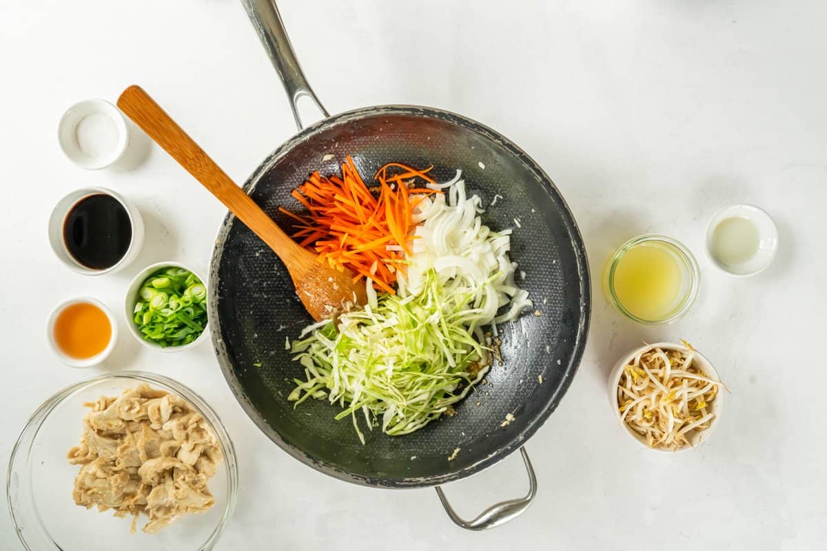 Cabbage onion and carrots in a frying pan with a wooden spoon. - 10