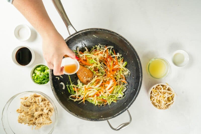 sherry drizzled into a frying pan filled with cabbage onions and carrots.