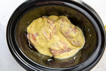 chicken breasts coated with ranch sauce in a crockpot.