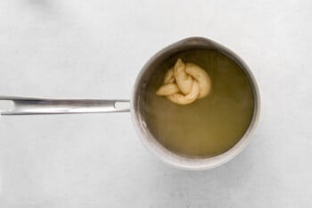garlic parmesan soft pretzel in a baking soda bath in a saucepan.