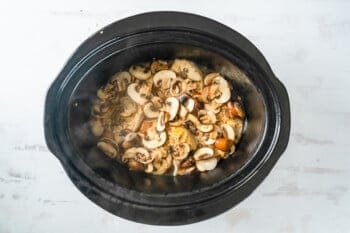 mushrooms and shallots over chicken breasts in a crockpot.