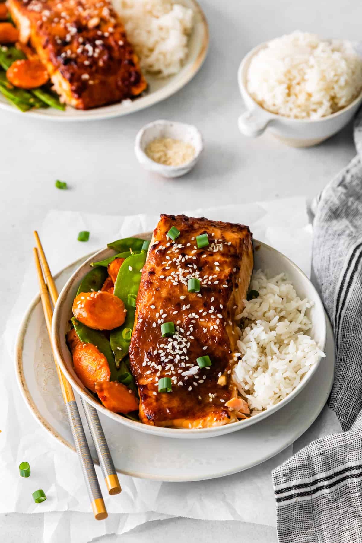 air fryer miso salmon in a white bowl with rice carrots and snap peas.