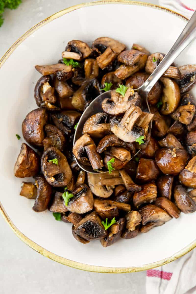 air fryer mushrooms in a white bowl with a spoon.