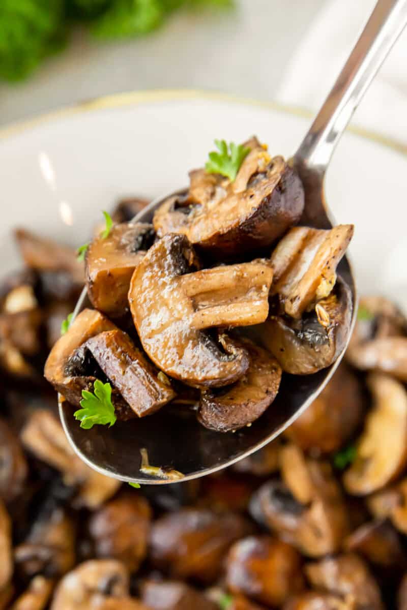 closeup of a spoonful of air fryer mushrooms in a white bowl.