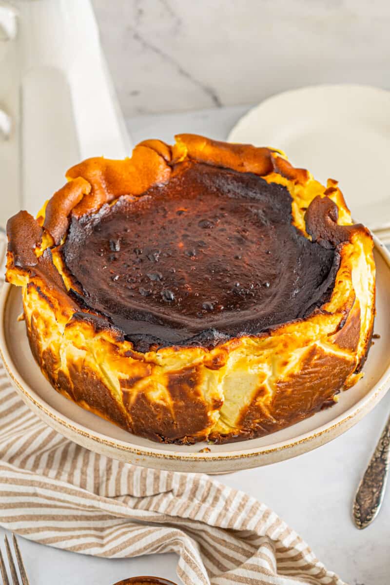 basque cheesecake on a white cake stand.