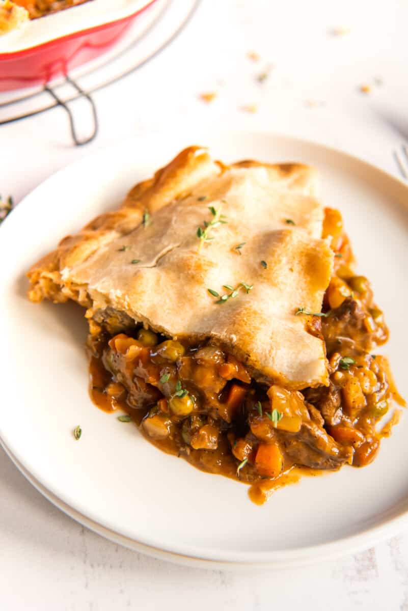 a slice of beef pot pie on a white plate.