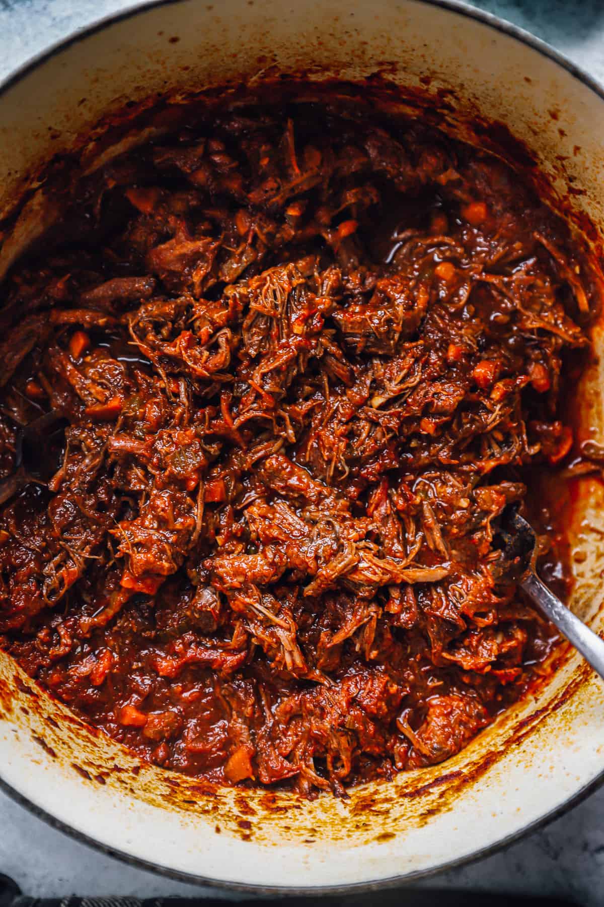 beef ragu in a dutch oven with a spoon.