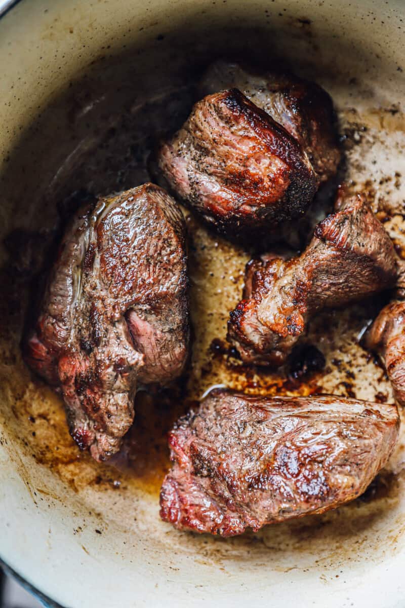 beef chuck roast pieces searing in a dutch oven.