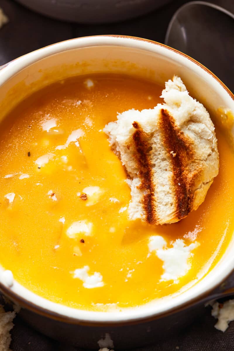 a bowl of creamy beer cheese soup with a piece of bread on top