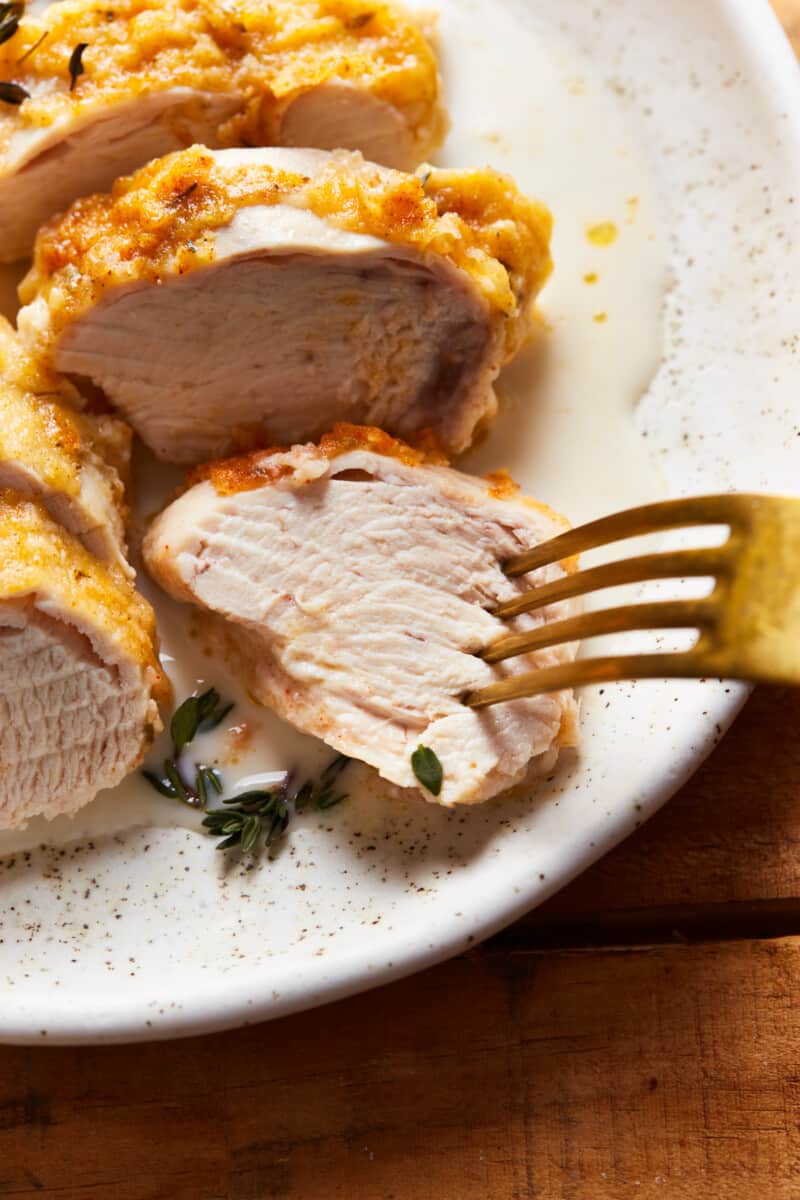 close up on a fork piercing a slice of baked chicken breast