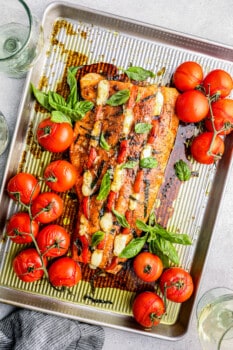 baking tray with stuffed salmon and vines of tomatoes