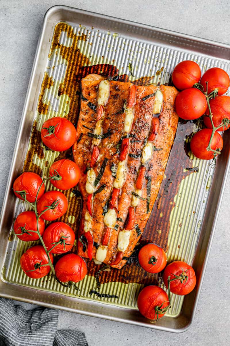 This Caprese Stuffed Salmon recipe is cheesy, delicious, and made on one pan! Baked salmon stuffed with tomato & mozzarella, paired with balsamic tomatoes. caprese stuffed salmon with balsamic tomatoes