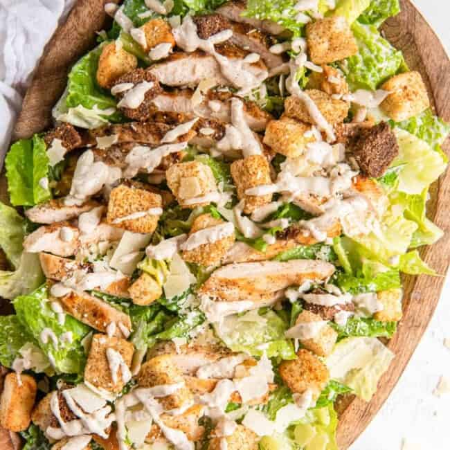 chicken caesar salad in a wooden serving bowl.