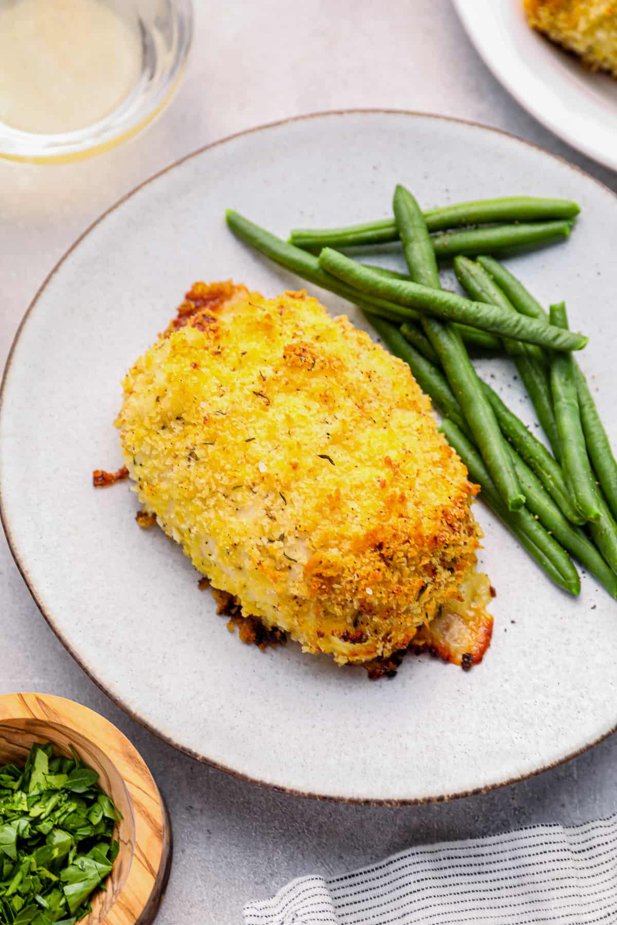 chicken cordon bleu baked on a white plate with green beans.