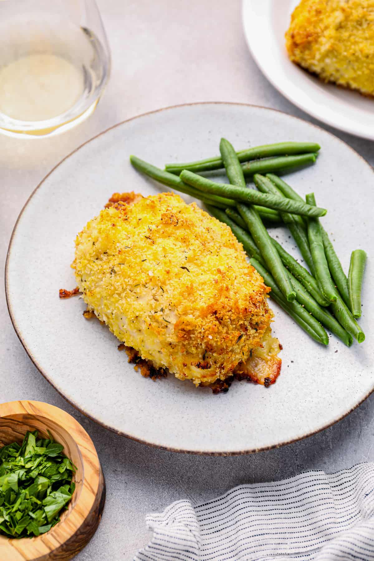 chicken cordon bleu baked on a white plate with green beans.