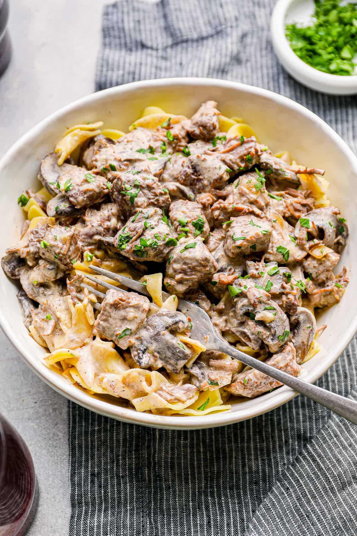 crockpot beef stroganoff in a white bowl with a fork.