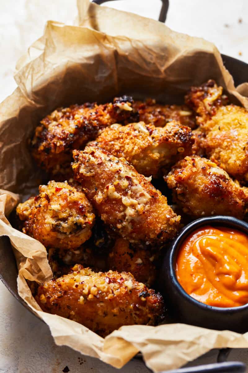 a basket of garlic parmesan wings with dipping sauce