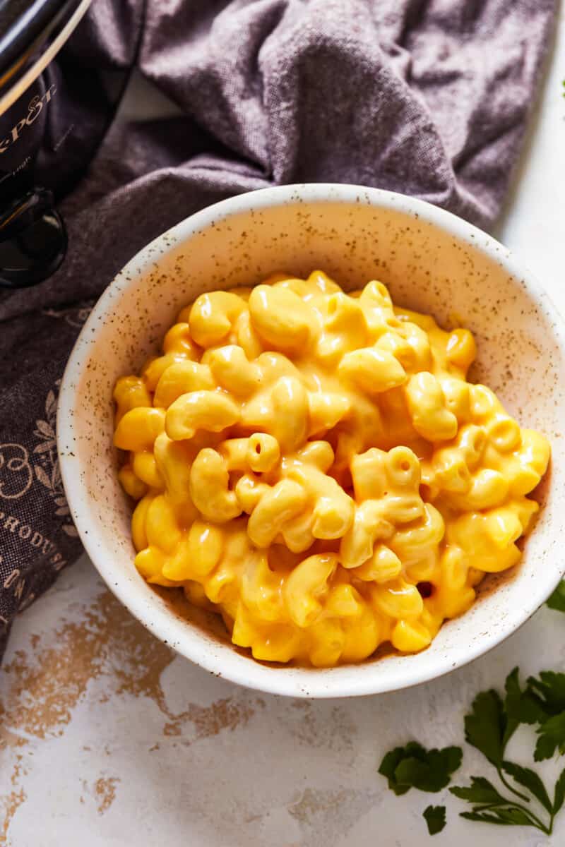 Crock Pot Mac and Cheese is a super simple recipe! This easy slow cooker macaroni and cheese makes the perfect side dish or weeknight dinner. It's virtually fool proof and comes out extra creamy and extra cheesy every time. Mac n cheese is always one of the best cheesy comfort foods around! bowl of crockpot mac n cheese
