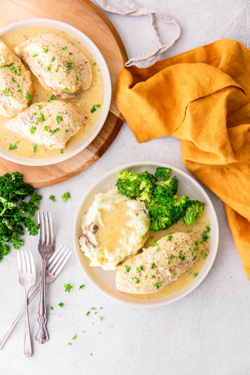 crockpot ranch chicken on white plates with mashed potatoes.