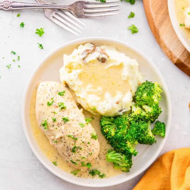 crockpot ranch chicken on a white plate with mashed potatoes.