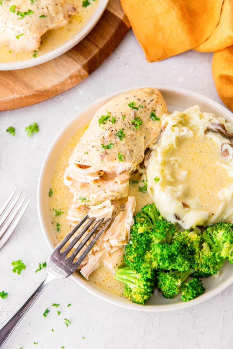 crockpot ranch chicken on a white plate with mashed potatoes and a fork.