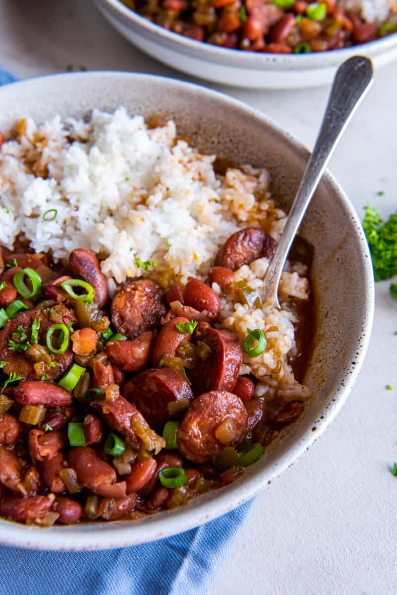 close up of crockpot red beans and rice in a white bowl with a fork.