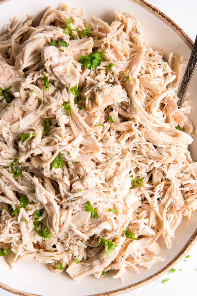 crockpot shredded chicken in a white bowl.