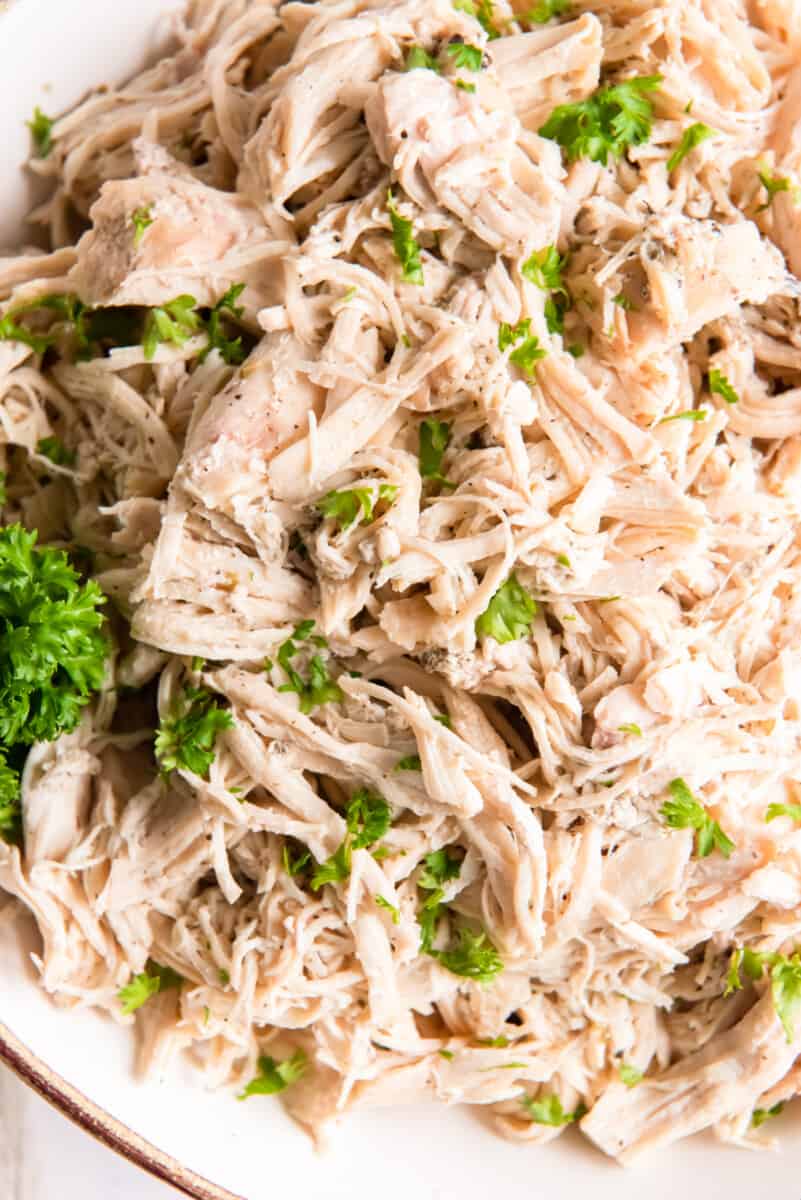 close up of crockpot shredded chicken in a white bowl.
