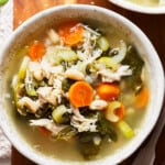 bowl of chicken soup with beans, spinach, and carrots