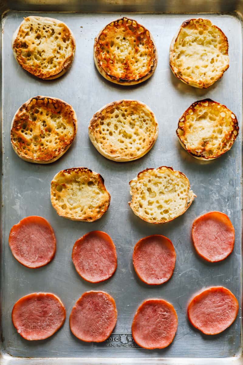 english muffins and ham slices on a sheet pan.