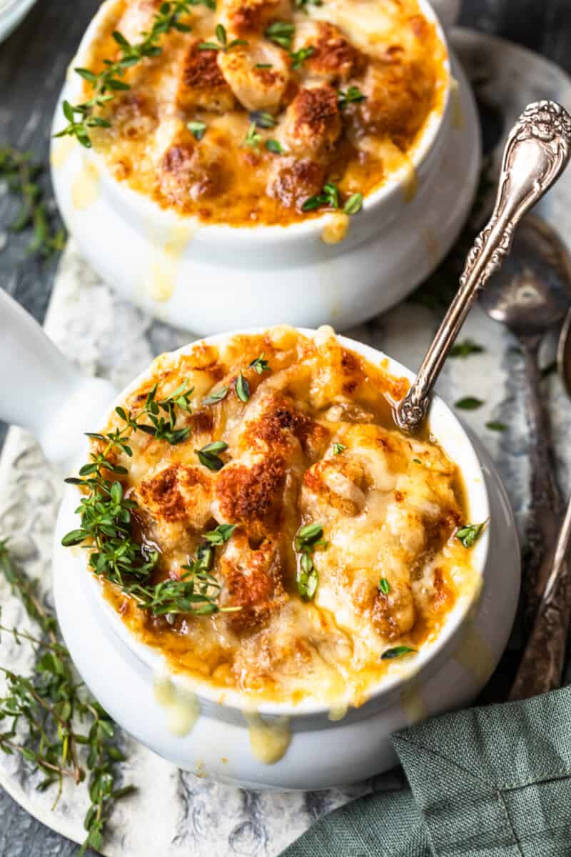 french onion soup in white bowls with a spoon.