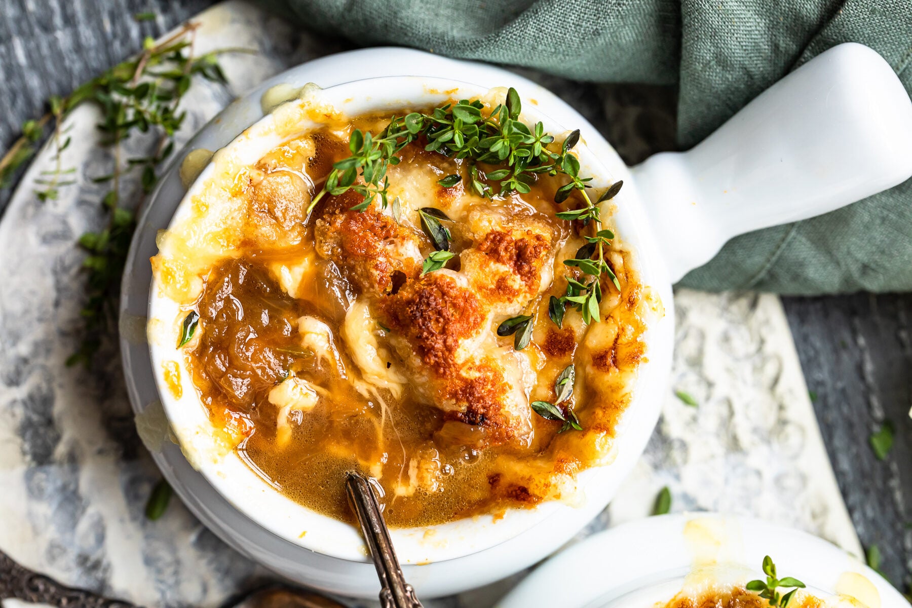 overhead view of french onion soup in a white bowl with a spoon.