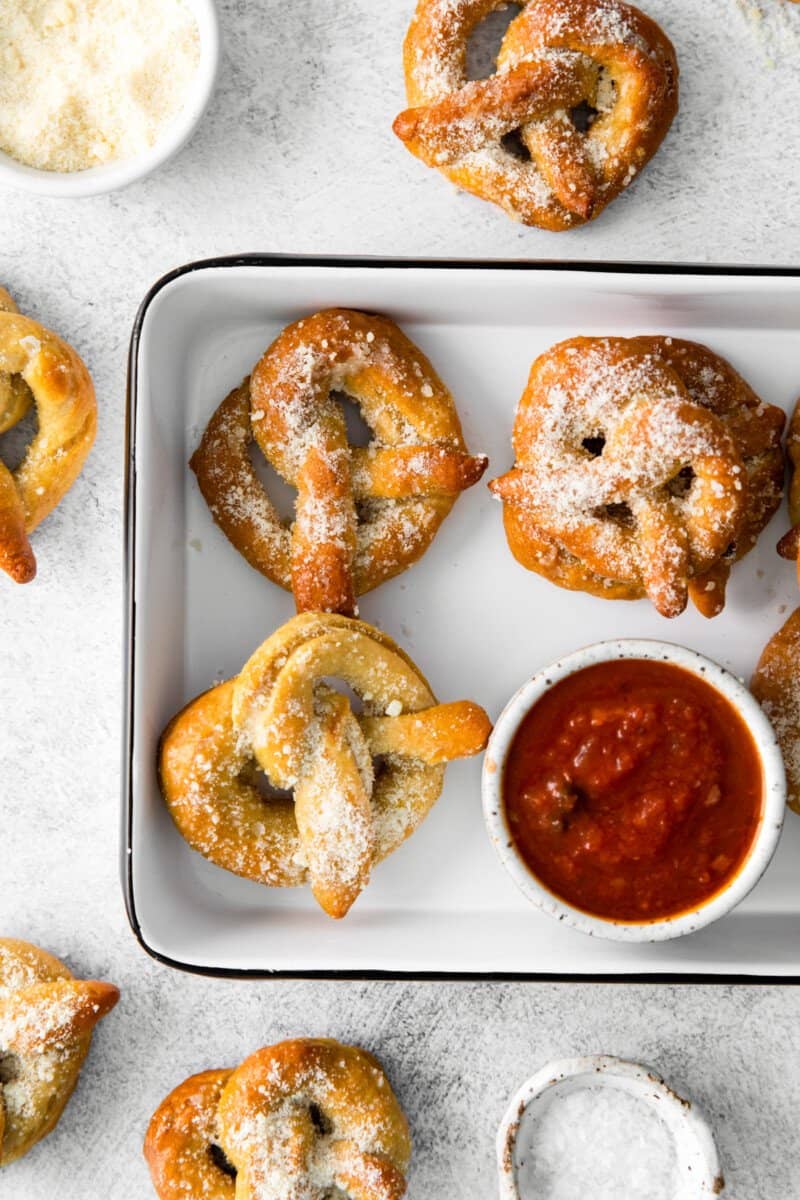 garlic parmesan soft pretzels in a white serving tray with marinara sauce.