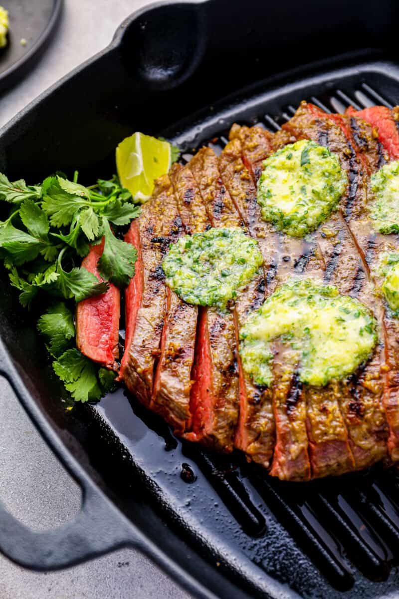flank steak topped with butter in a grill pan