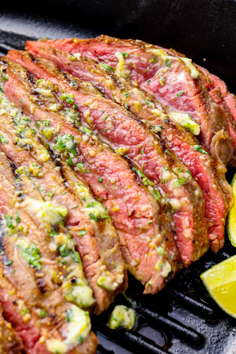 close up on thin slices of flank steak covered in cilantro lime butter