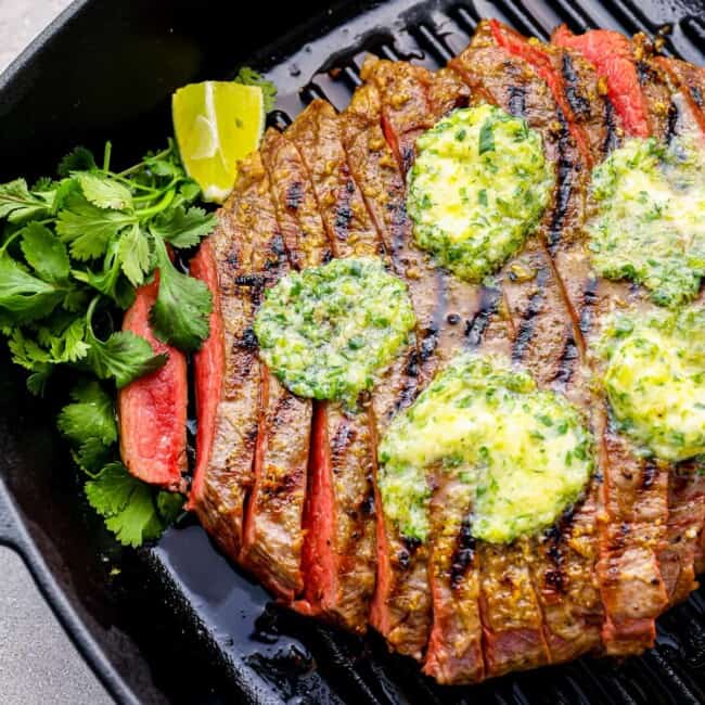 grilled flank steak sits in a black grill pan