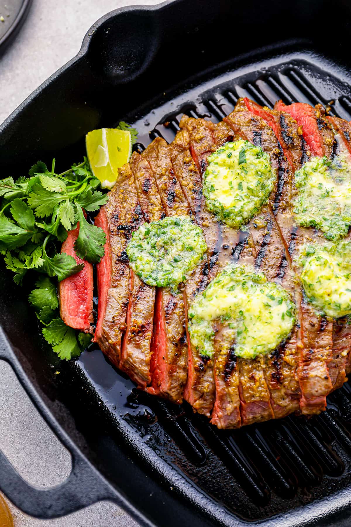grilled flank steak sits in a black grill pan
