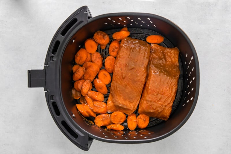 salmon and carrots in an air fryer basket.