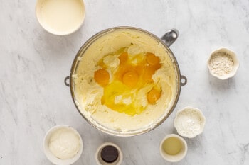 eggs added to cheesecake batter in a stainless mixing bowl.
