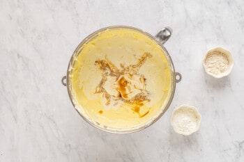 sour cream heavy cream and vanilla added to cheesecake batter in a stainless mixing bowl.