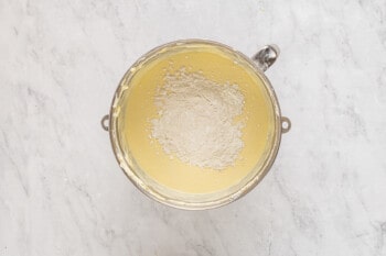cornstarch and flour added to cheesecake batter in a stainless mixing bowl.
