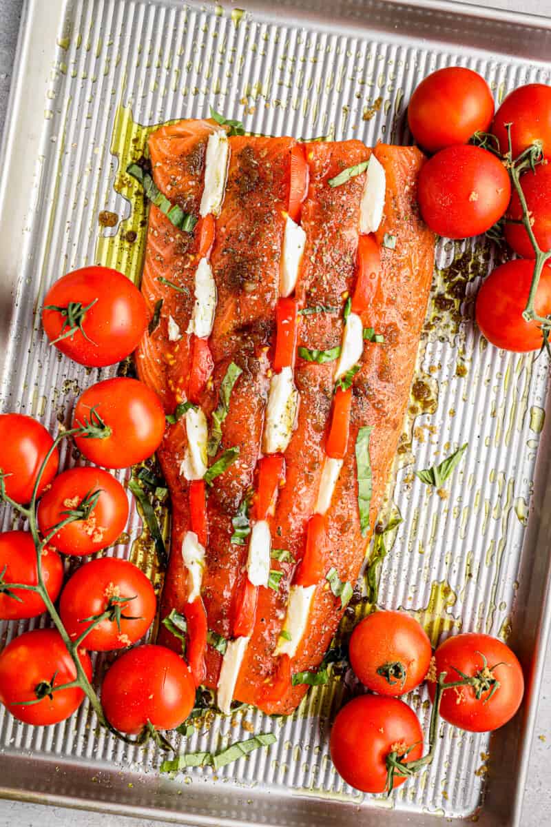This Caprese Stuffed Salmon recipe is cheesy, delicious, and made on one pan! Baked salmon stuffed with tomato & mozzarella, paired with balsamic tomatoes. how to make caprese stuffed salmon
