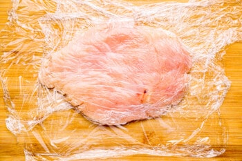 thinly pounded chicken breast on plastic wrap.