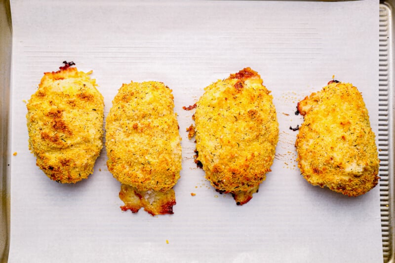 4 baked chicken cordon bleu pieces on parchment paper.