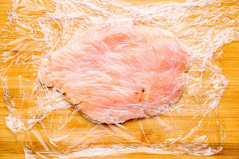 thinly pounded chicken breast on plastic wrap.