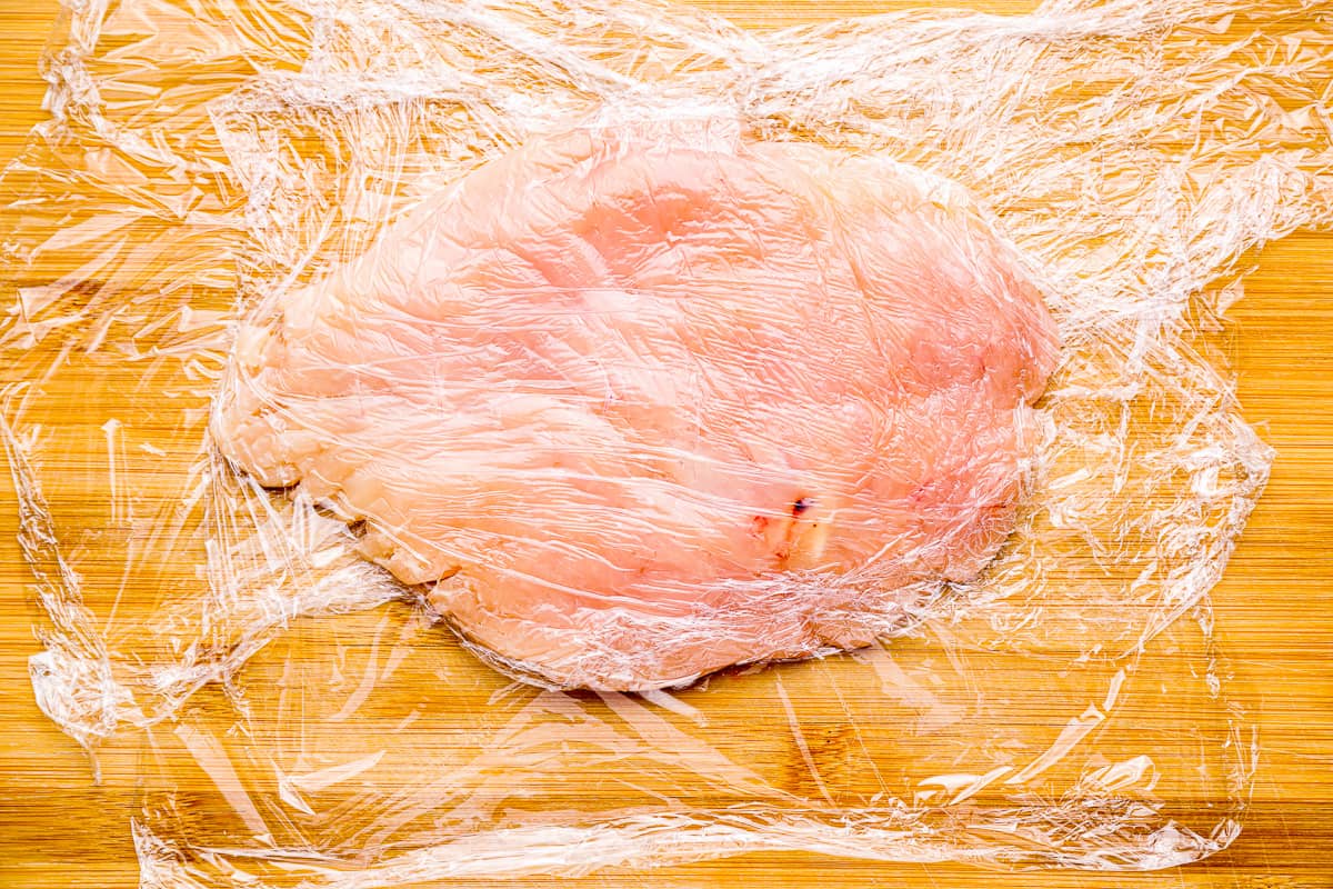 thinly pounded chicken breast on plastic wrap.