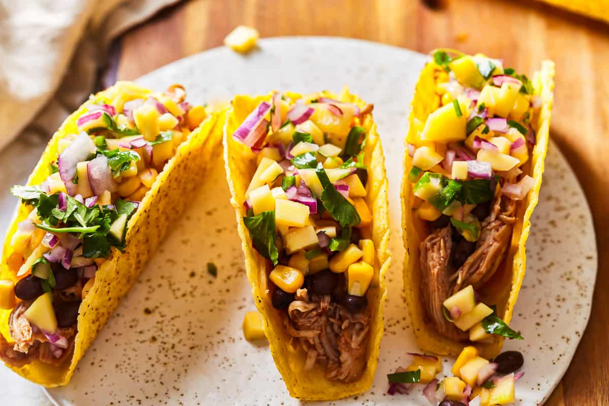 shredded chicken tacos topped with mango salsa, corn, and black beans