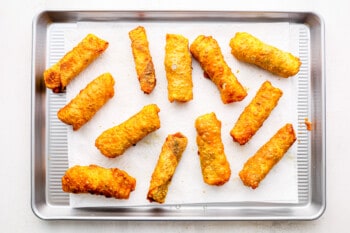 12 egg rolls on a lined baking sheet.