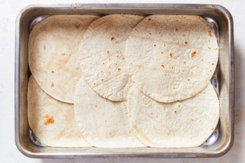tortillas arranged in the bottom of a casserole pan
