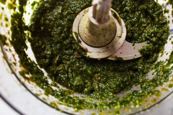 close up on green salsa mixture in a food processor